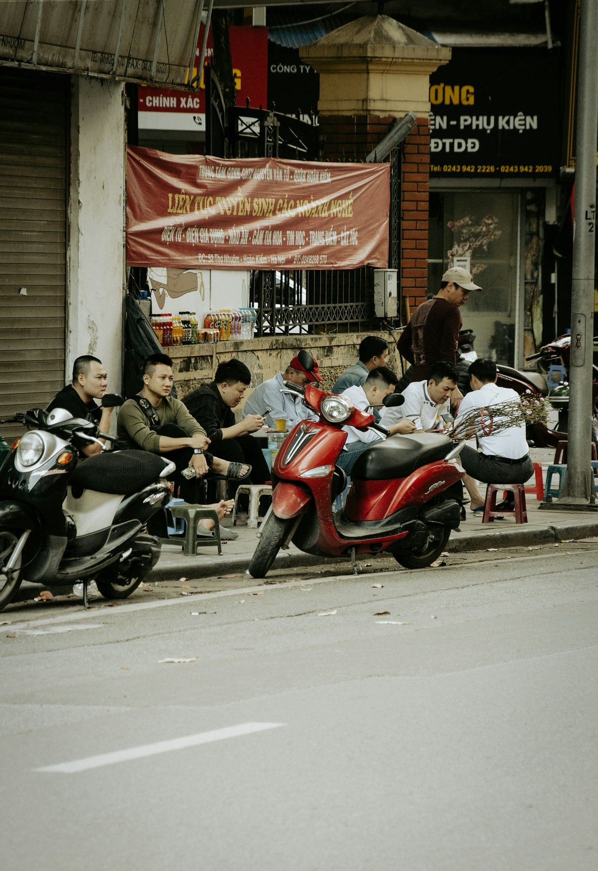 Scooters parked in a row along a Vietnamese street outside a cafe