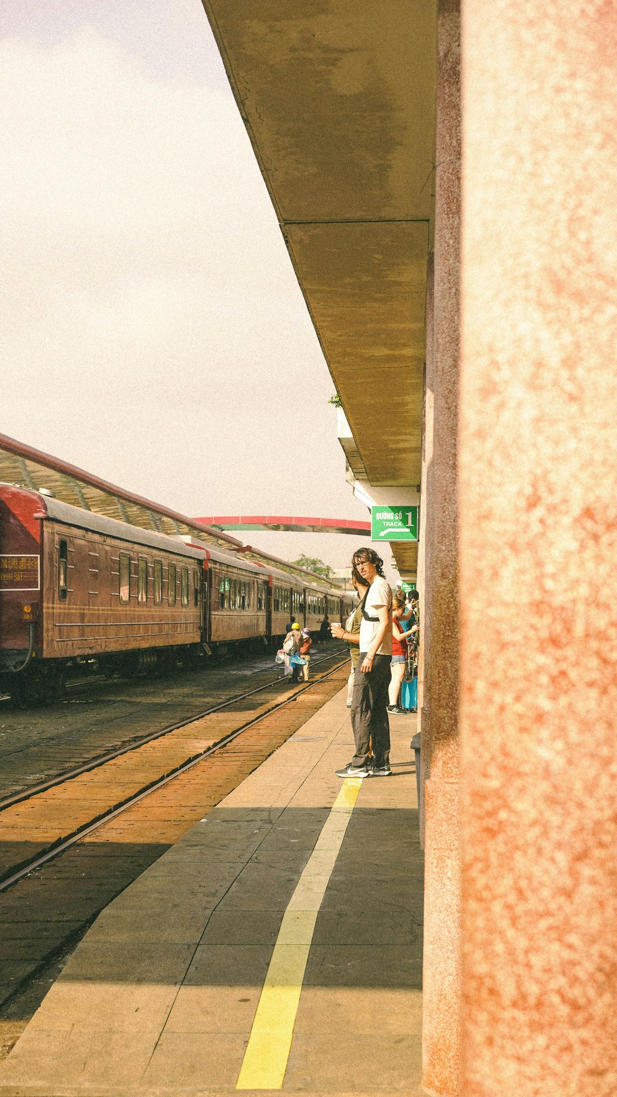 A traveller standing on the platform beside a Reunification Express carriage