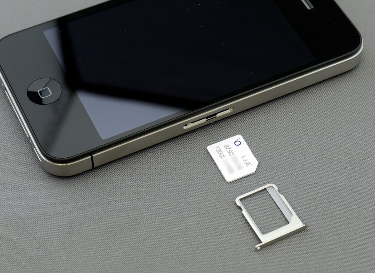 A phone's SIM tray opened with the card beside it