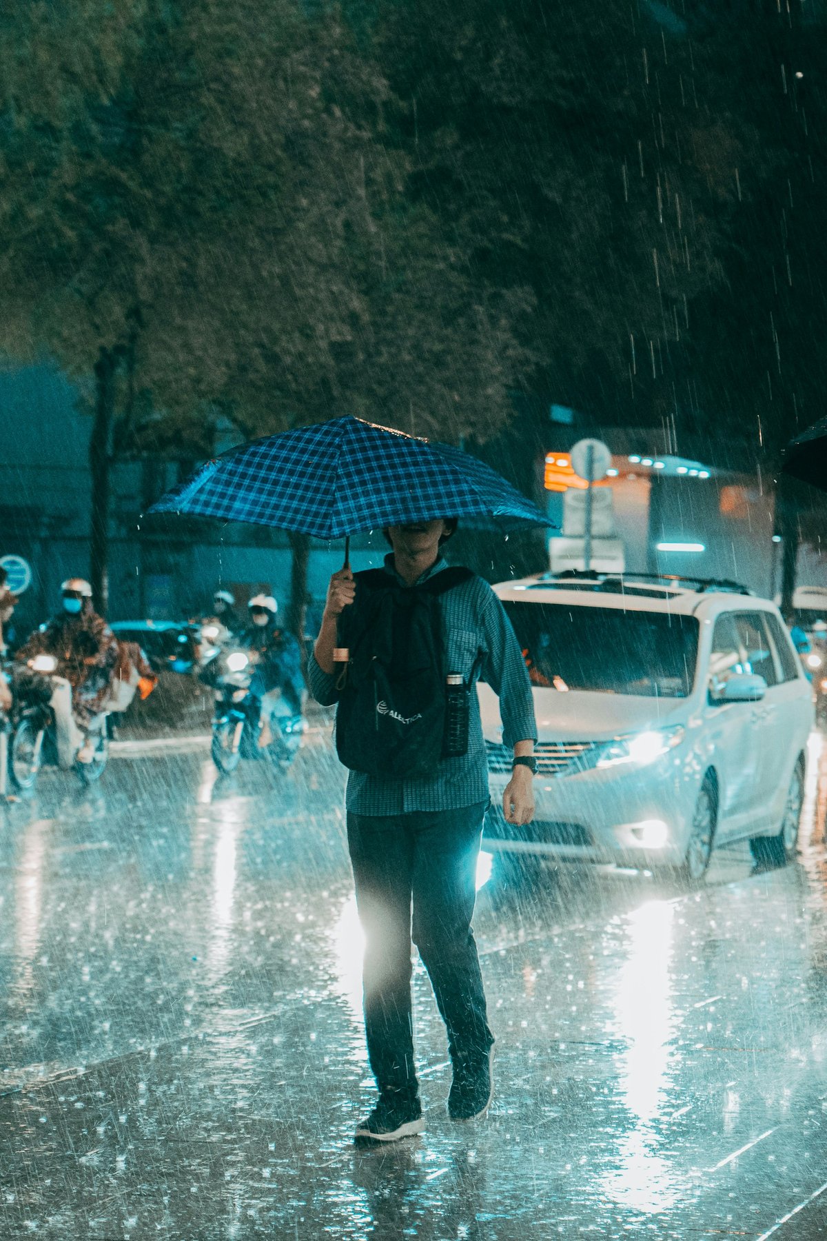 Motorbike riders in plastic ponchos during a heavy downpour on a Vietnamese city street