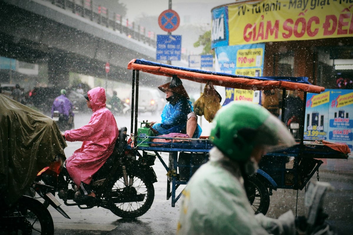 Travellers in cheap plastic rain ponchos riding through a wet Vietnamese street
