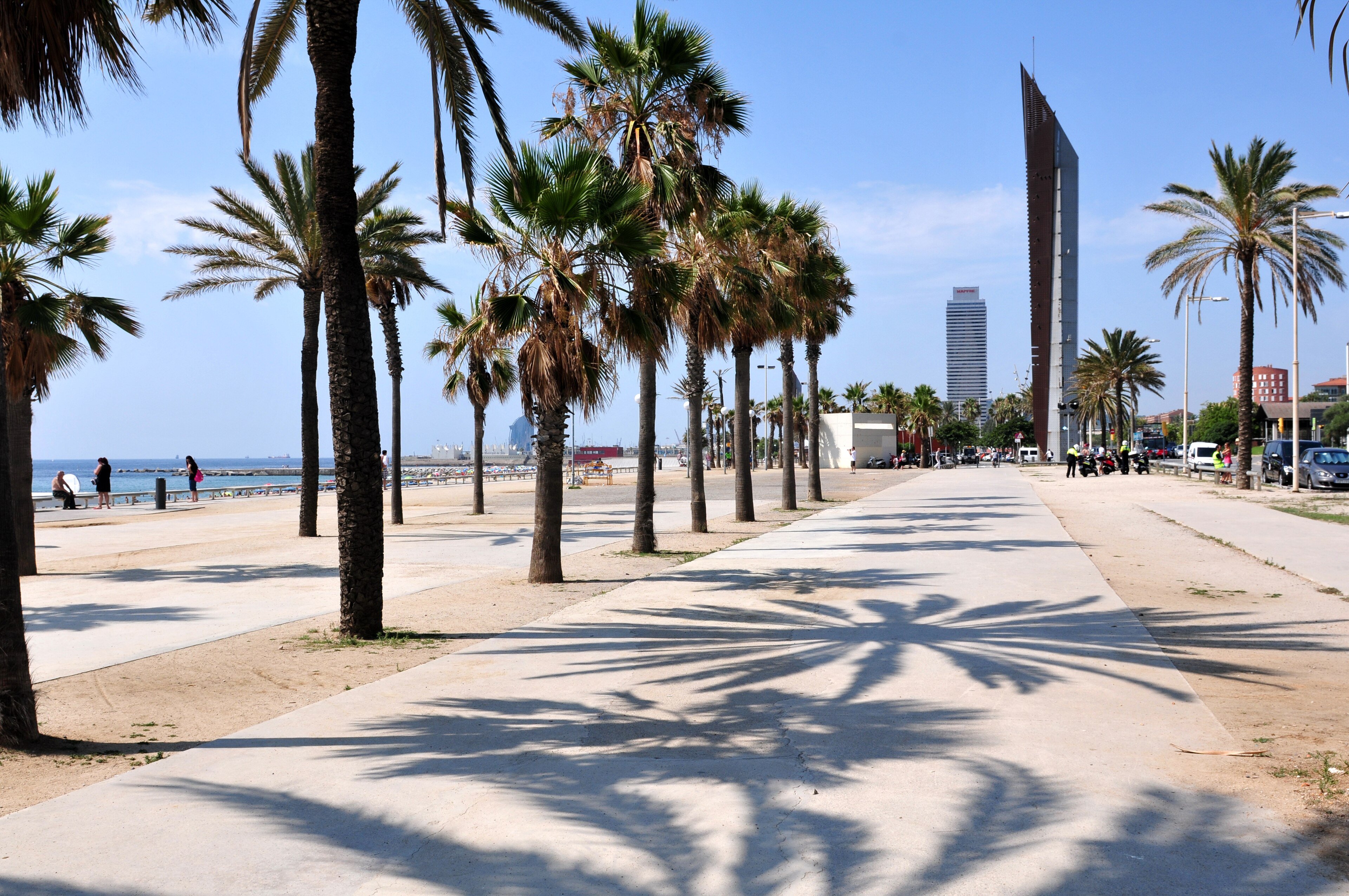 A sweeping Barcelona beach scene — sand, the boardwalk, swimmers, the city behind