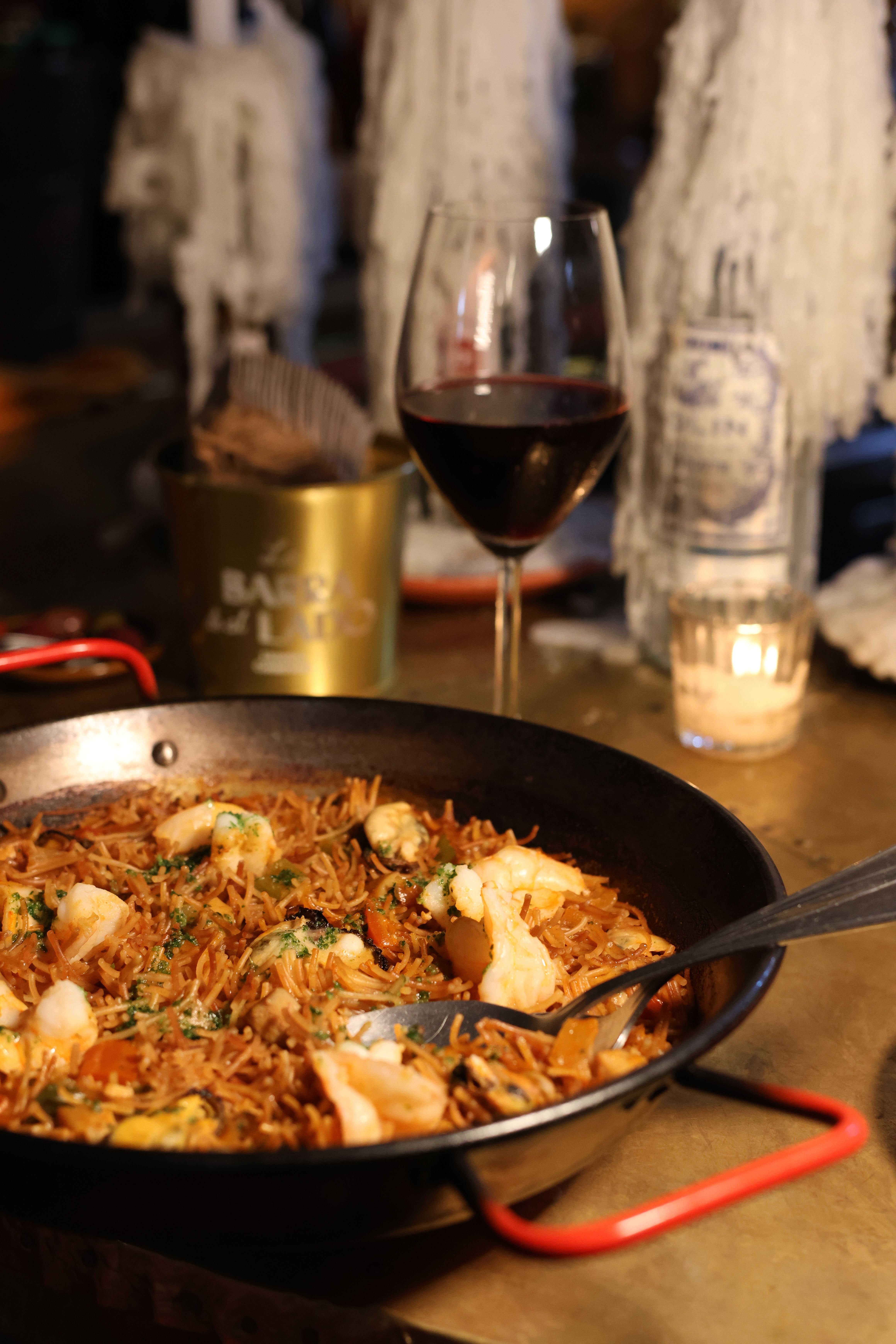 A proper seafood paella in a wide pan, golden with real socarrat, not neon yellow