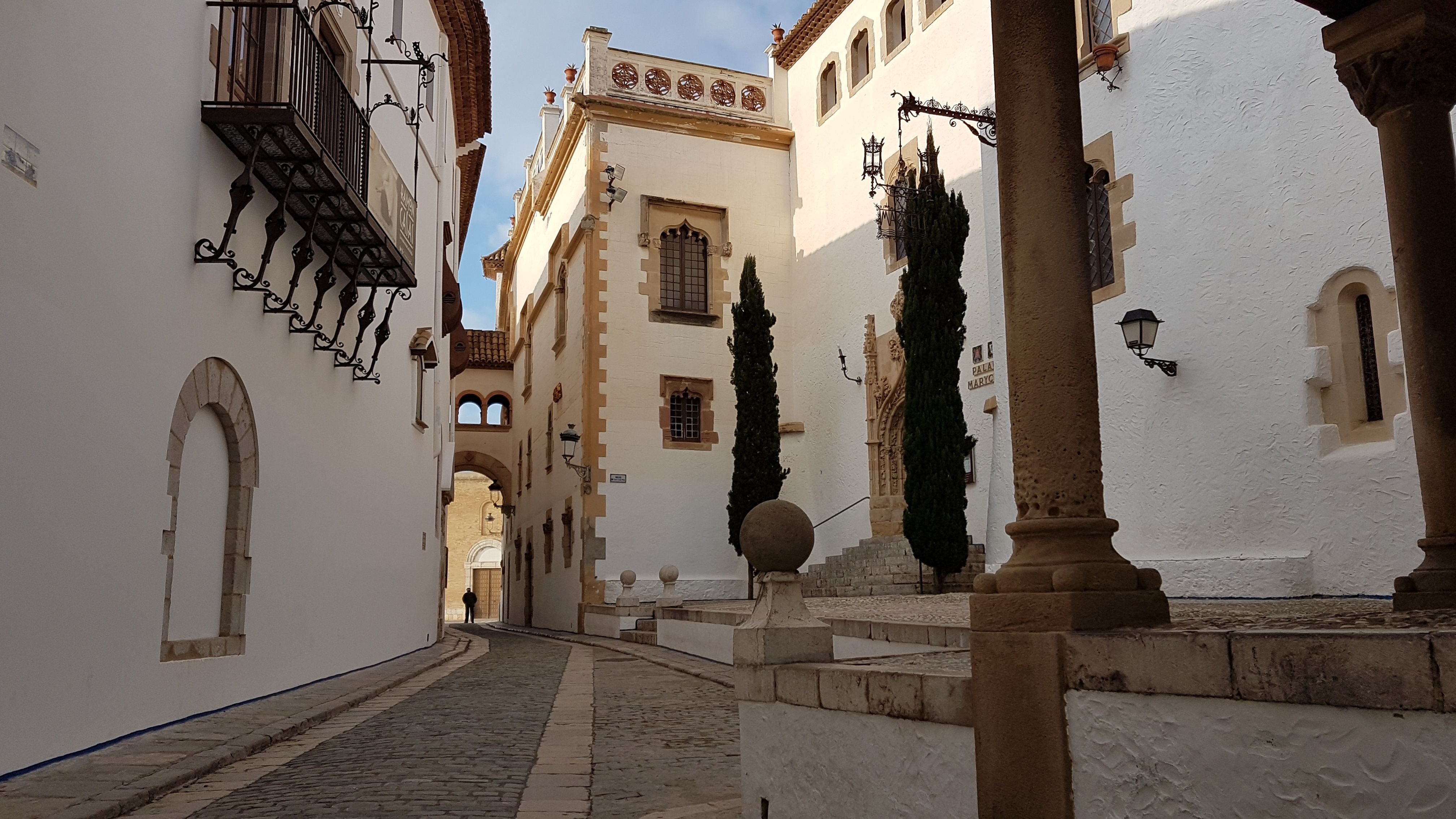 A Sitges beach scene or a whitewashed old-town lane with flowers