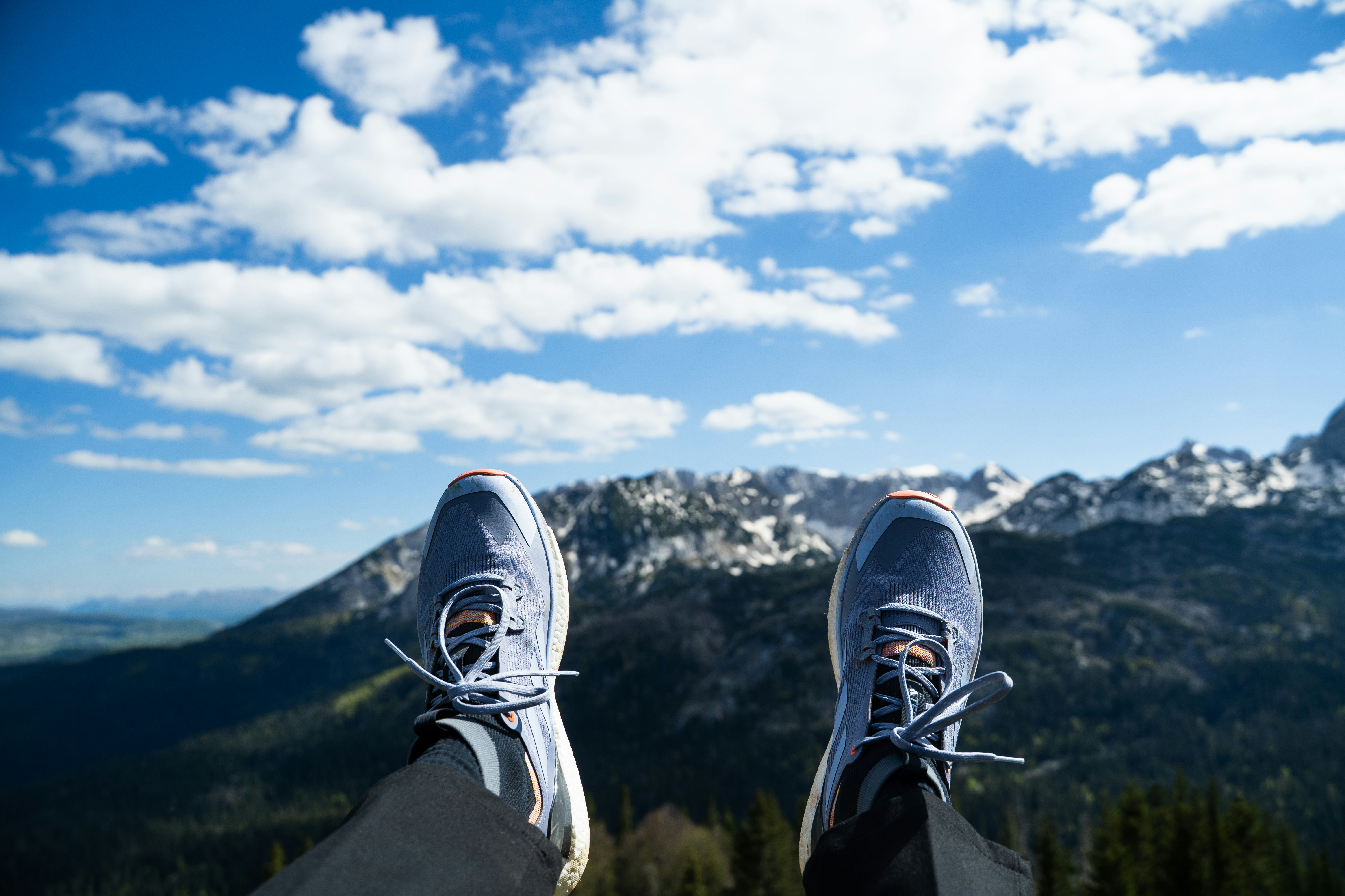 A flat-lay of travel packing essentials — comfortable shoes, day bag, layers, sunglasses
