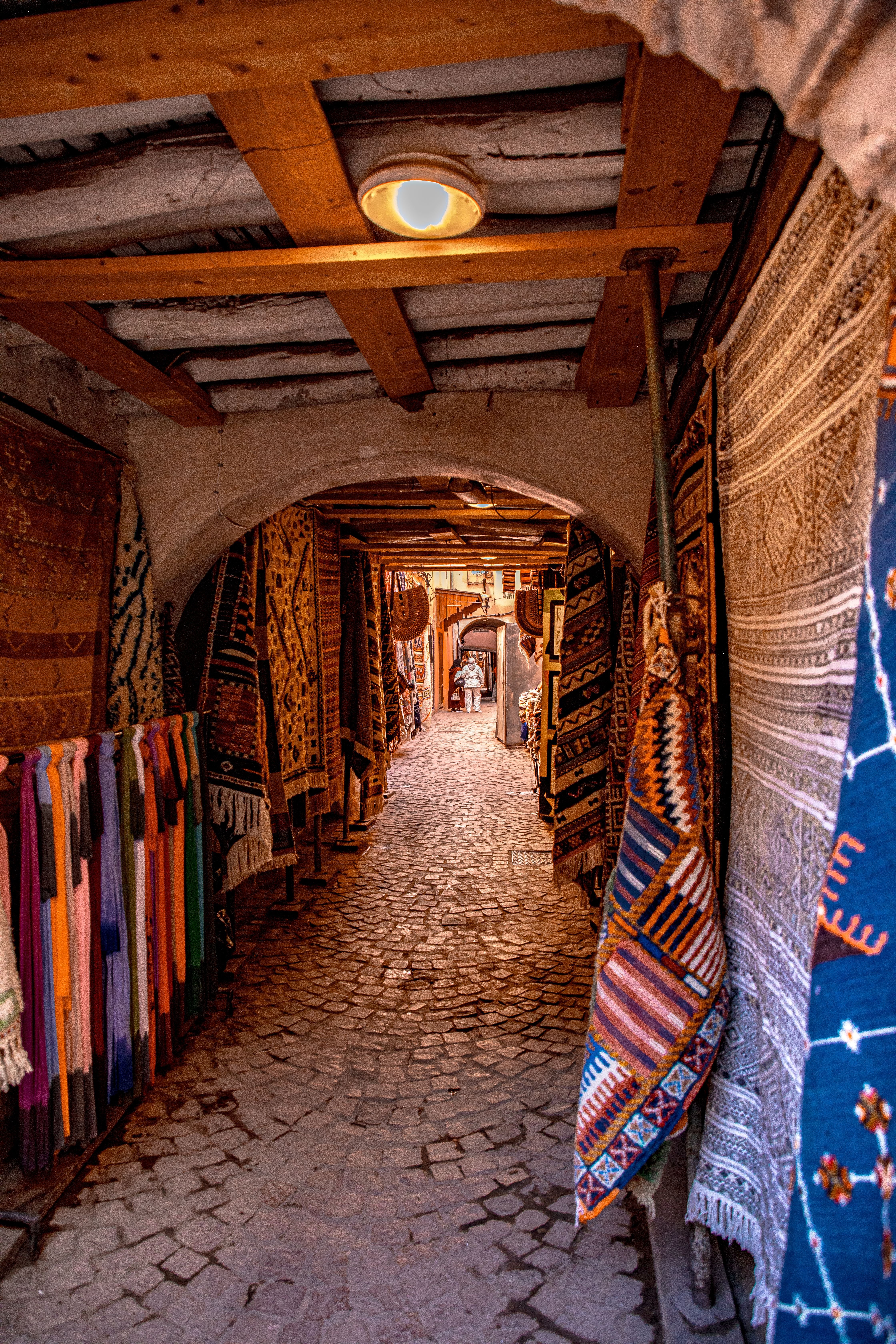 A colorful display of Moroccan rugs and textiles in a souk stall