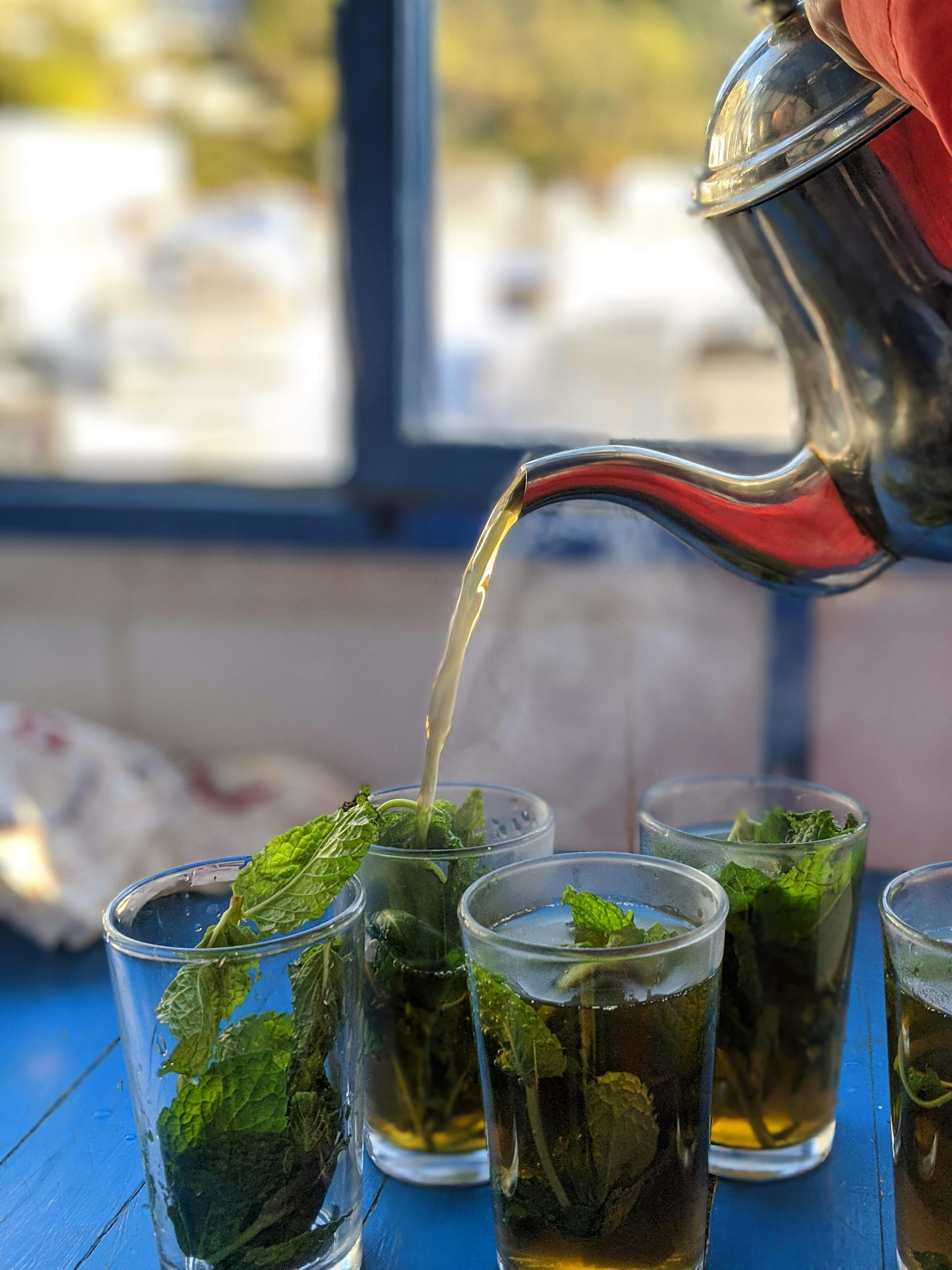 A friendly Moroccan shopkeeper pouring mint tea for visitors