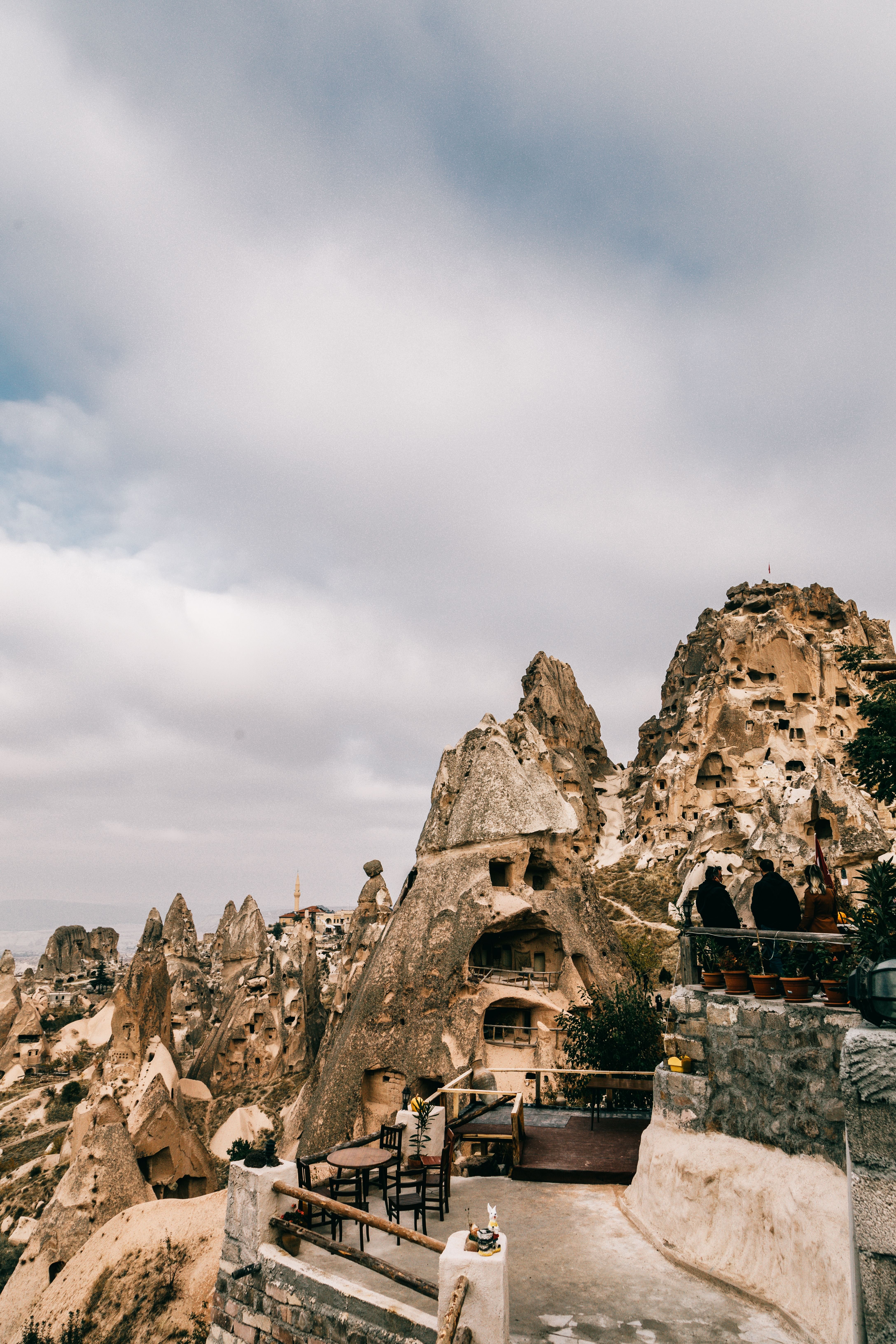 A stylish Cappadocia cave hotel terrace at sunrise with balloons rising beyond, no recognizable faces