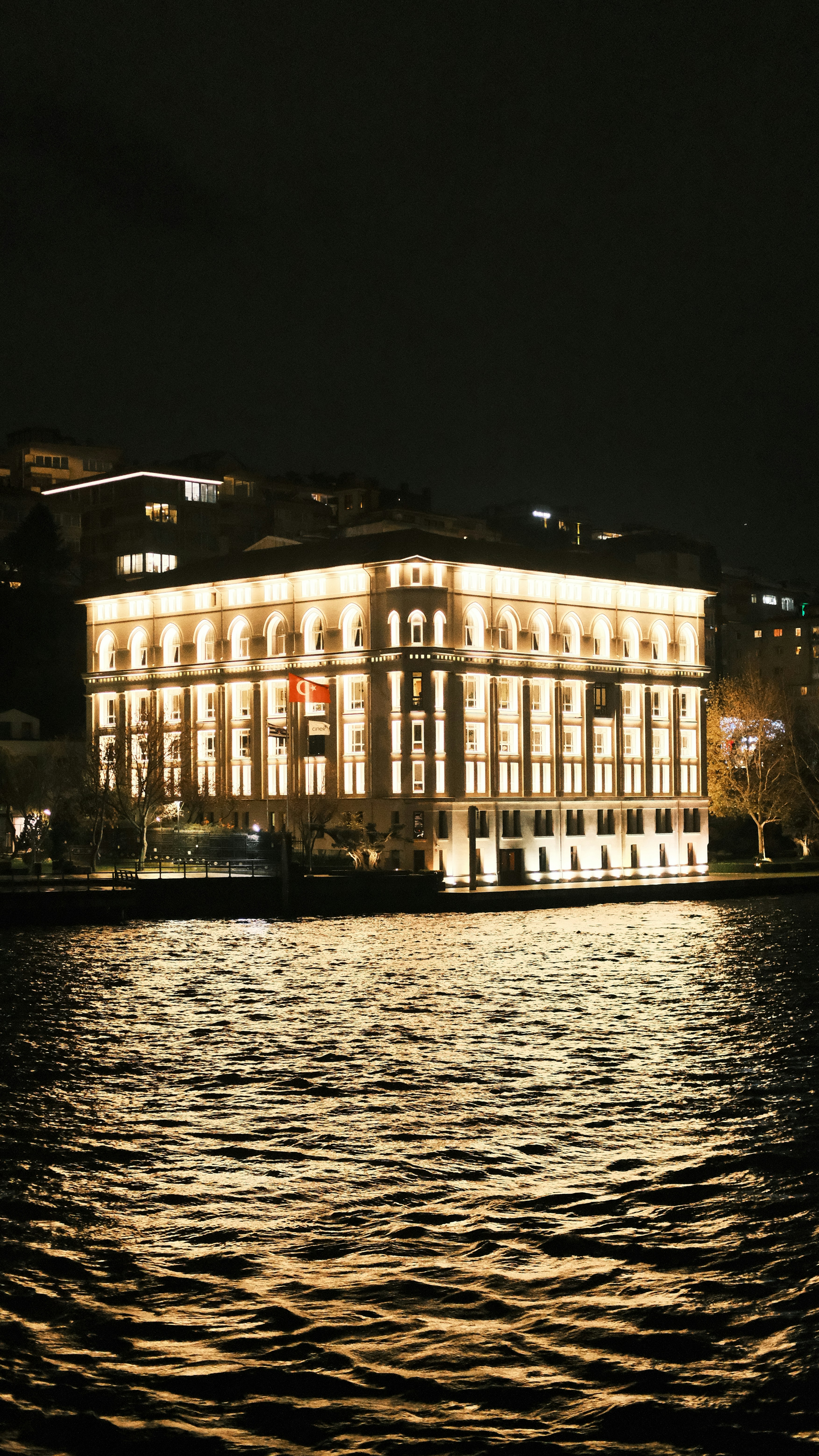 A luxurious Bosphorus-front hotel terrace at dusk with the water and city lights, no recognizable faces