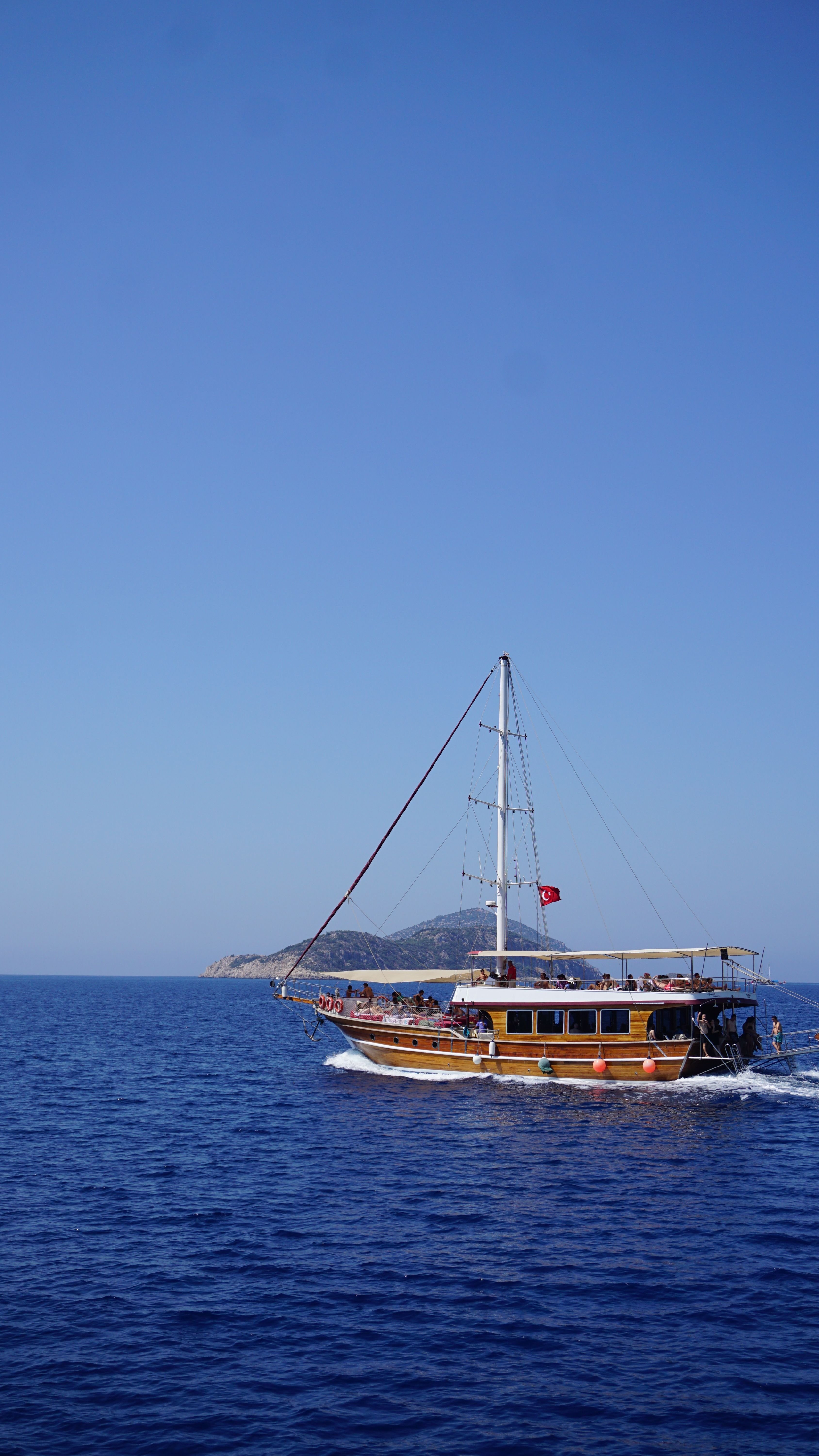 A wooden gulet anchored in a turquoise Turkish bay surrounded by pine hills, no recognizable faces