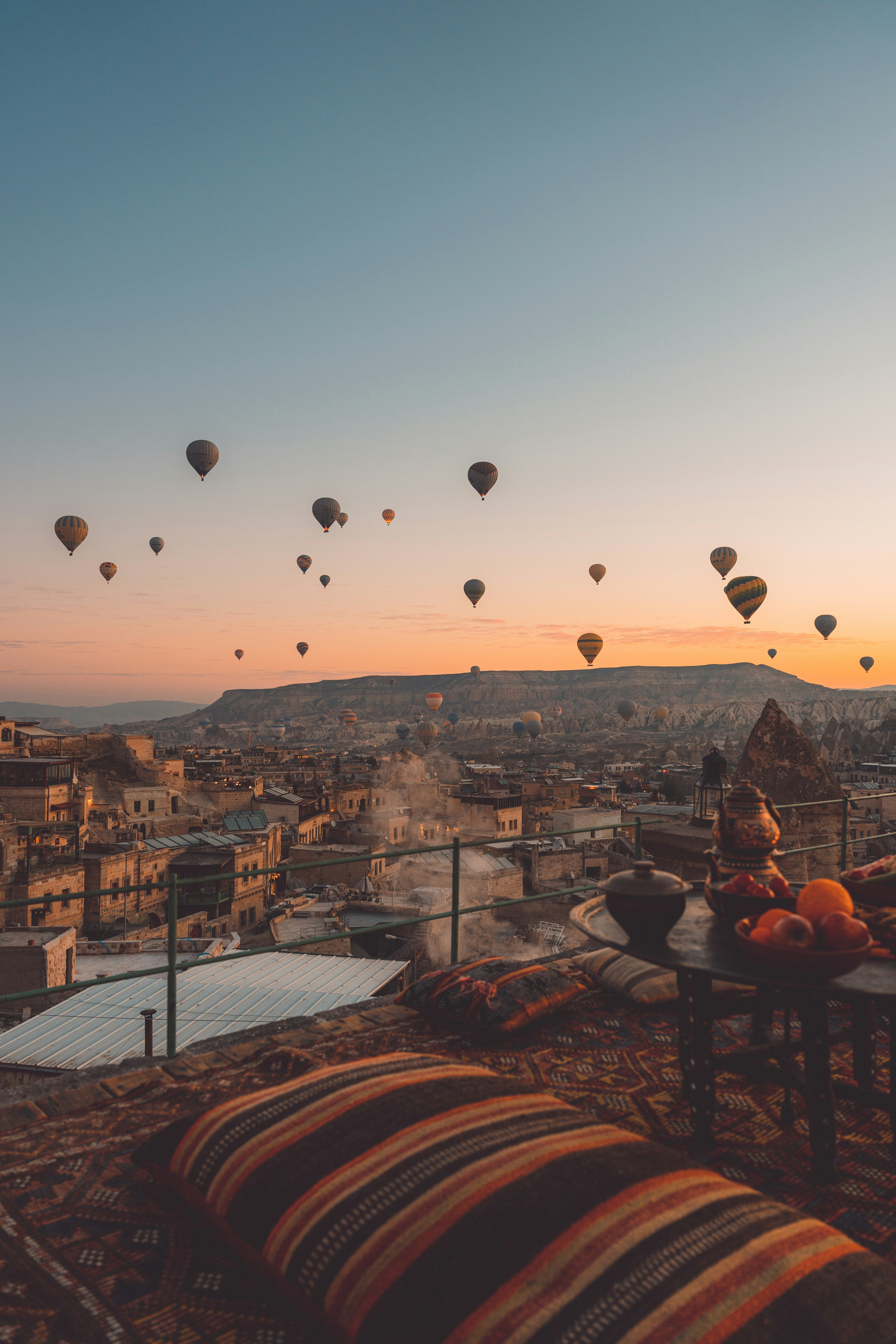 A cave hotel terrace with breakfast laid out and balloons rising in the background
