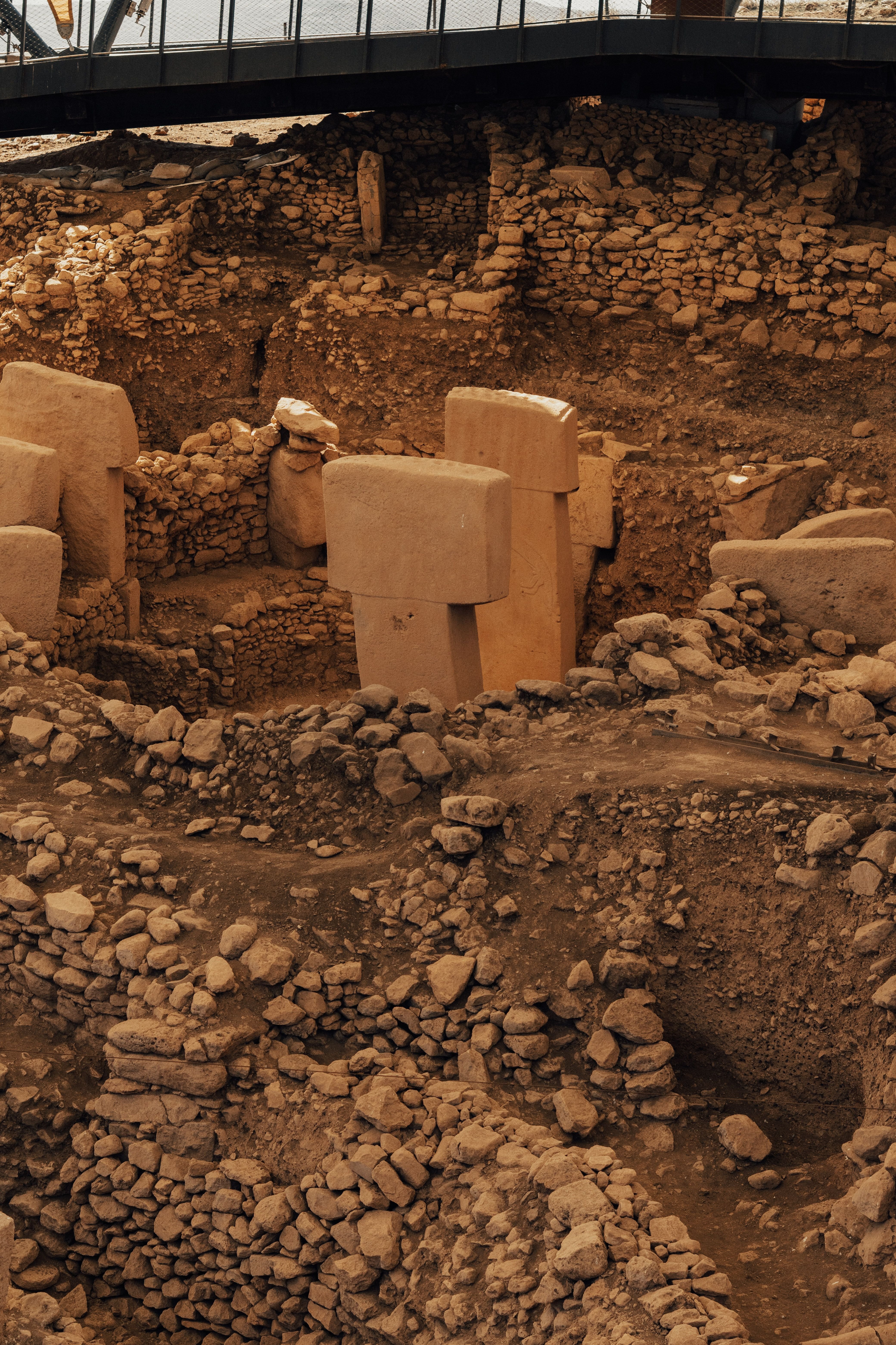 The carved T-shaped megalithic pillars of Göbeklitepe under their protective canopy, no recognizable faces