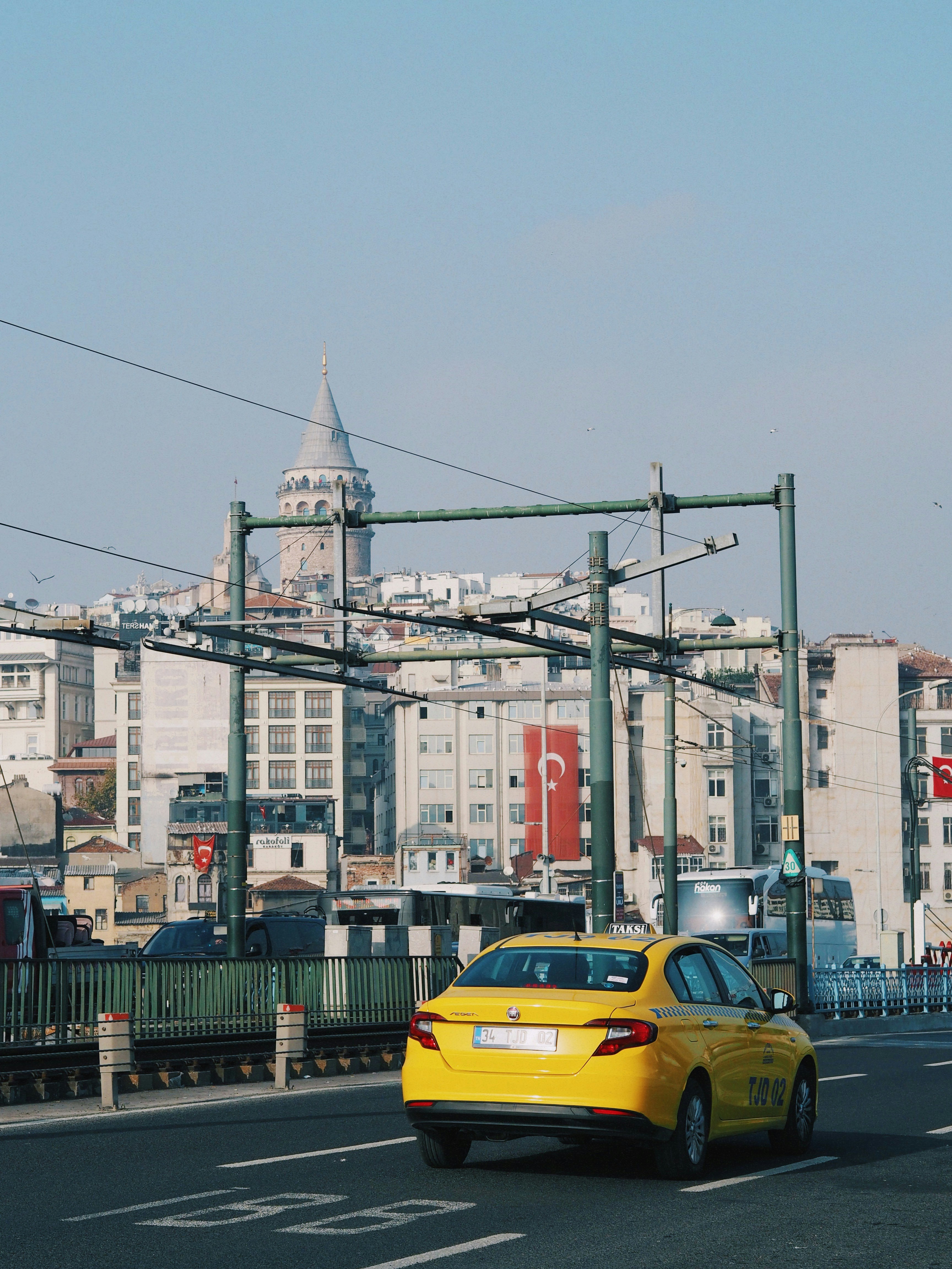 A yellow Istanbul taxi on a road with the city skyline behind