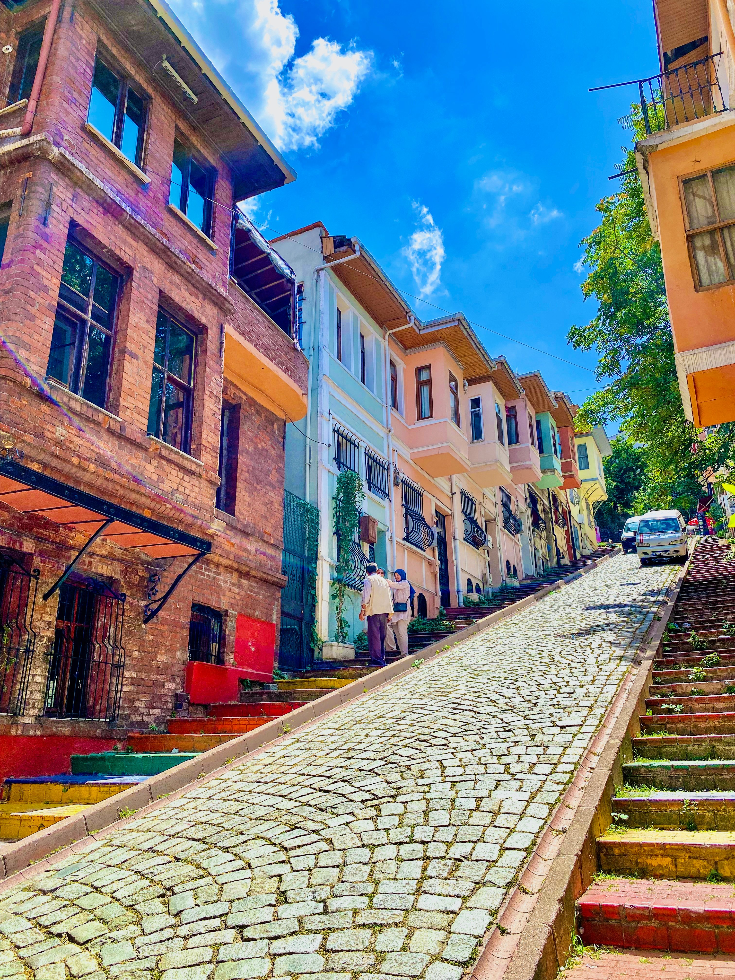 A narrow, colorful street in Balat or Karaköy with cafes and hanging lights