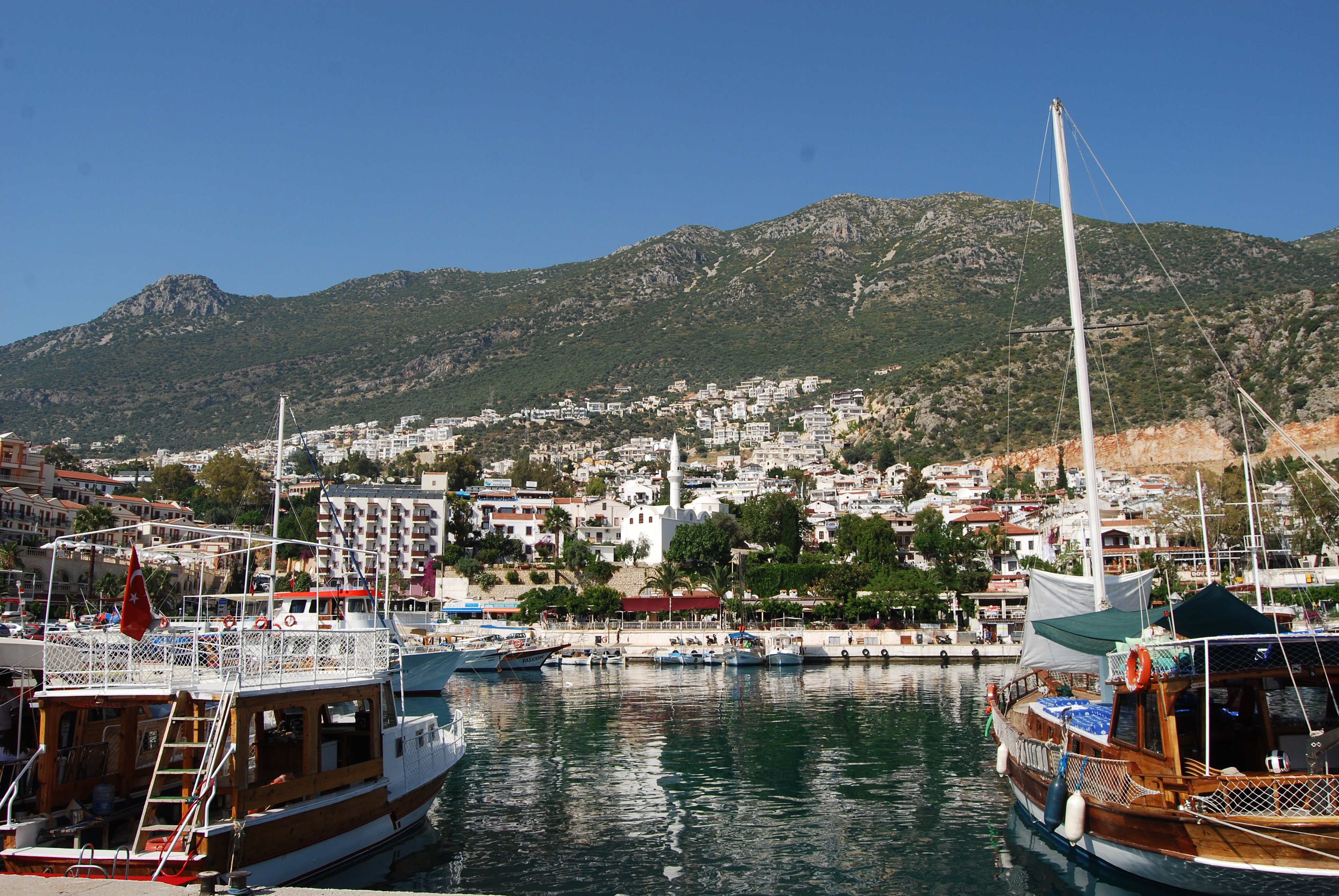 Whitewashed harbor town of Kaş with bougainvillea and blue sea, no recognizable faces