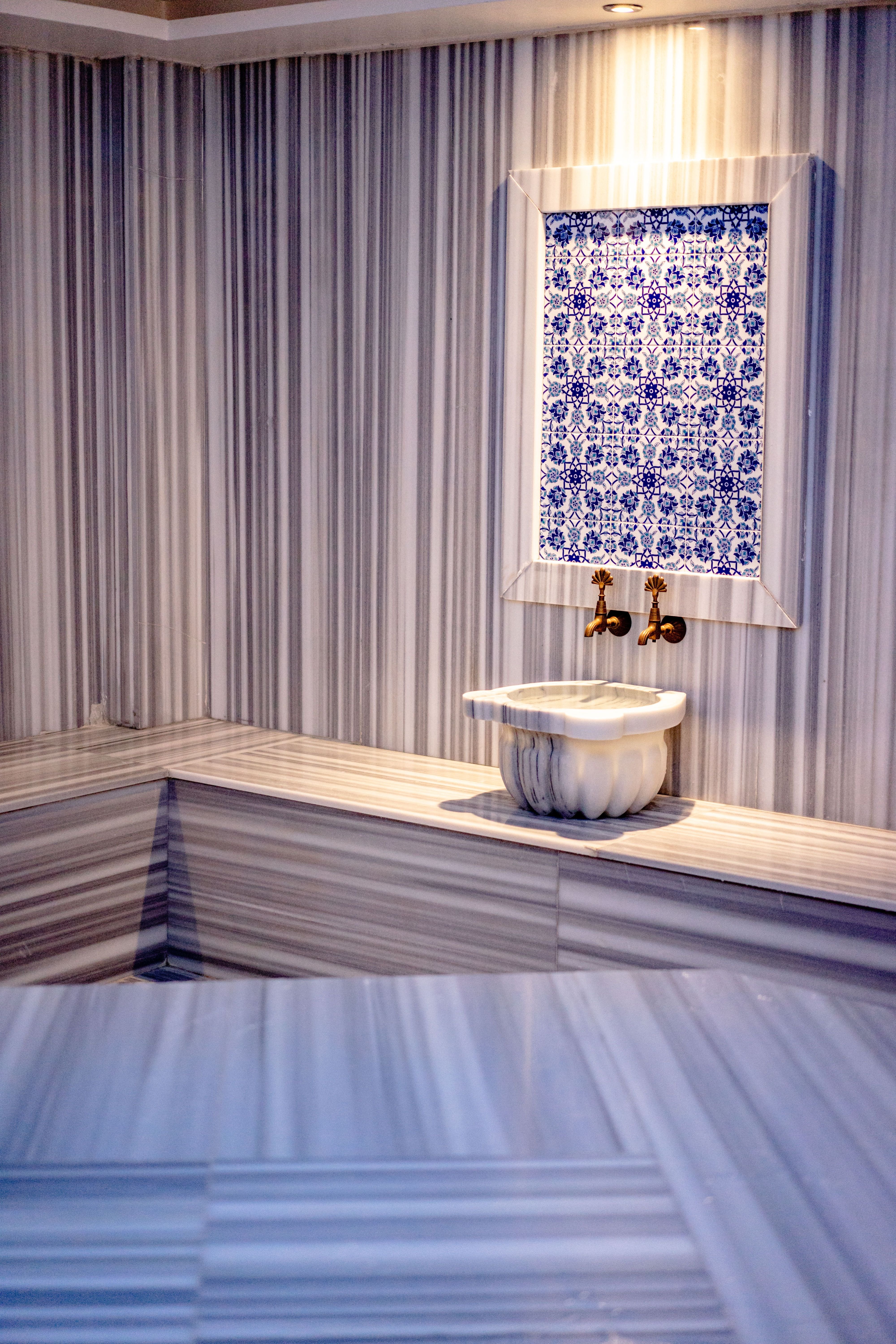 The interior of a historic Turkish hammam — marble domed room with the central heated platform, no recognizable faces