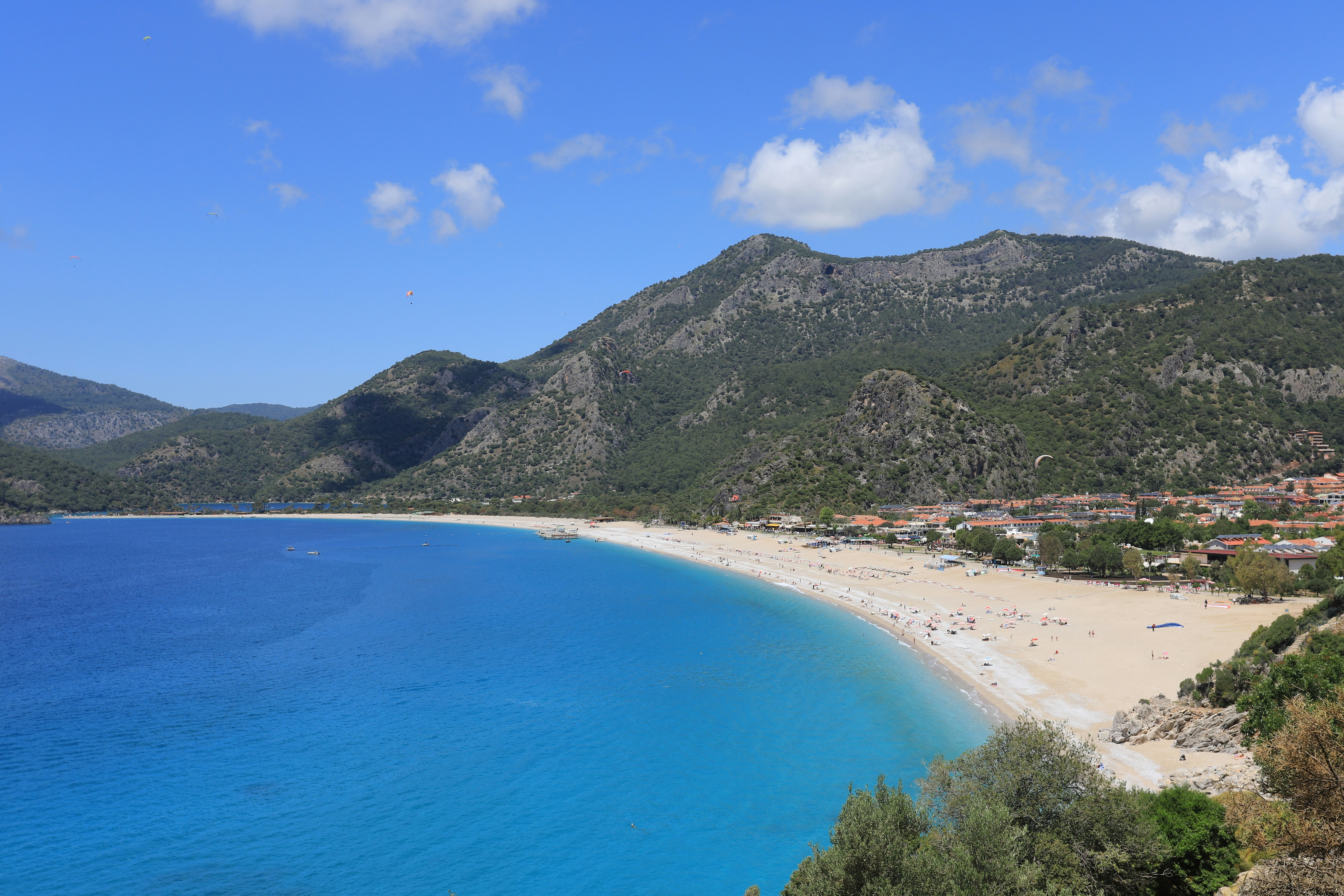 Sweeping Turquoise Coast view — a turquoise bay framed by pine-covered mountains, no recognizable faces